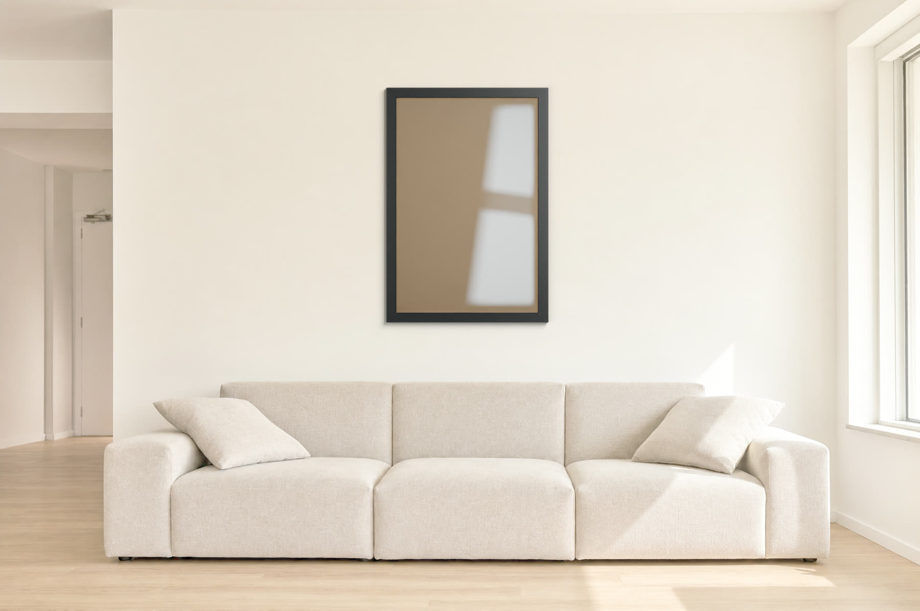 Moldura preta 60x90 com perfil de 4 cm na parede de uma sala ampla e clara, sobre um sofá bege
